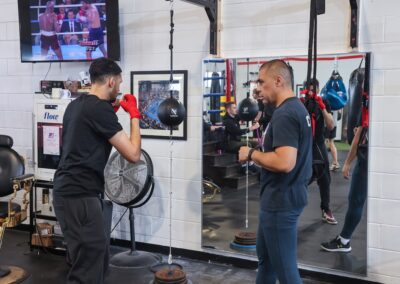 Two men are practicing boxing in a gym.