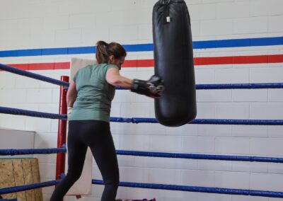 A woman is boxing in the ring with a punching bag.